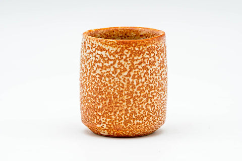 Front view of the teacup showing the speckled orange Shino glaze and plum blossoms.