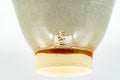 Low-angle view of one Hagi-yaki cup showing the unglazed buff foot ring with a glaze run down the base.