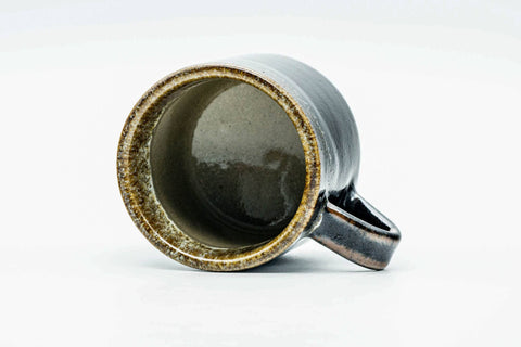 Looking down into the cup at its glazed interior, with the handle visible.