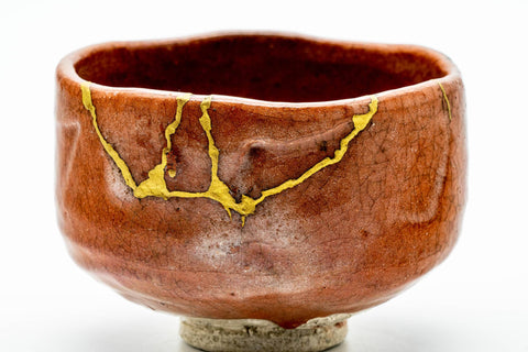 Front view emphasising the gold kintsugi seams running down the orange raku body.