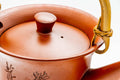 Top-down view of the red shudei dobin with lid on, showing the lid knob and gold handle mounts