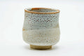 Side view of the yunomi, showing the pinholed shino glaze and orange tones.