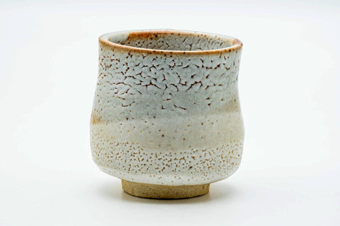 Side view of the yunomi, showing the pinholed shino glaze and orange tones.