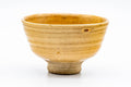 Ido-shaped Ki-Seto chawan with a deep yellow crazed glaze, viewed from the front, showing the spiralling 'rokurome' throwing lines and flared rim.