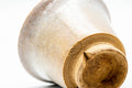 A cup tilted to reveal its glazed interior and unglazed foot