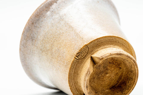 A cup tilted to reveal its glazed interior and unglazed foot