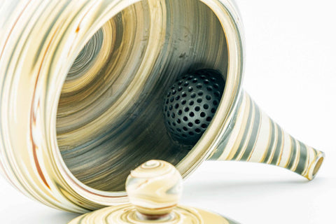 The teapot with its lid removed, revealing the built-in ceramic mesh strainer inside.