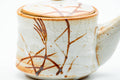 Close-up of the rust-orange brushed grass-and-floral design on the teapot body.