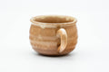 Three-quarter view of the teacup showing the side handle and tan drip glaze.