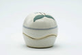 Front view of the closed domed kogo, white glaze with a painted flower and a gold-lined seam.