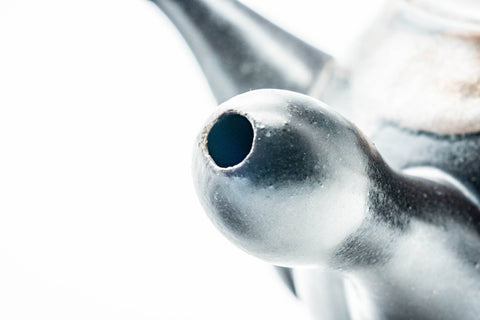 Close-up of the spout and body showing the matte black glaze and brown drip detailing.