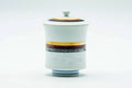 White porcelain Arita-yaki lidded yunomi teacup banded with blue, gold and grey stripes, lid on, front view.