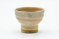 Front view of the beige Hagi teacup showing its tall foot and warm glaze.