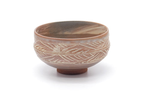 Pink-white hakeme chawan, three-quarter view emphasising the carved comb pattern around the lower body