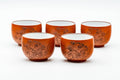 The five red teacups arranged together, front view, showing their white-glazed interiors.
