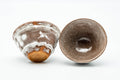 One cup tipped to show the glazed interior beside its mate.