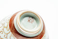 A cup tipped to reveal its foot and a red maker's mark.