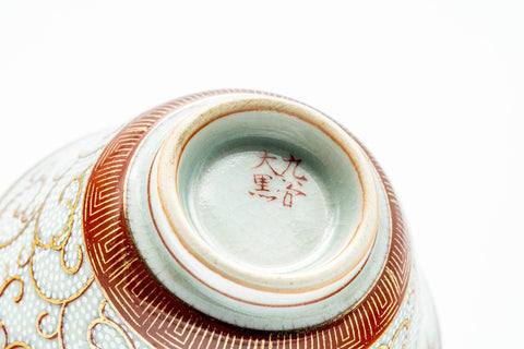 A cup tipped to reveal its foot and a red maker's mark.