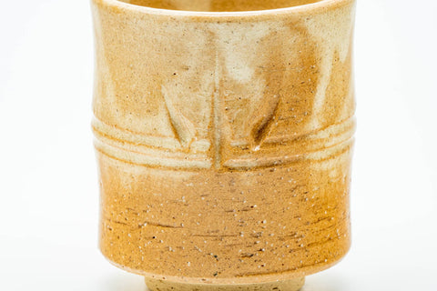 Close-up of a single cup showing the engraved bamboo design and drip glaze.