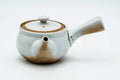 White-glazed Tokoname side-handle kyusu with exposed brown clay at the base, lid on, shown from the side.
