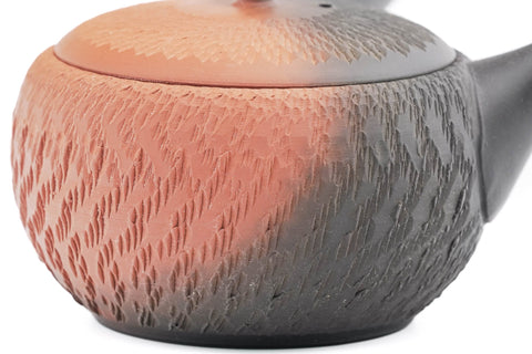 Black-and-red yōhen Tokoname kyusu teapot with side handle and dimpled tochiri texture - top-down view showing the red-and-black yōhen colouring