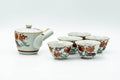 Full Kutani-yaki tea set laid out: white side-handle kyusu teapot with red floral decoration alongside five matching yunomi teacups.