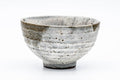 Grey milky drip-glazed matcha chawan with a ridged, textured body, three-quarter view.