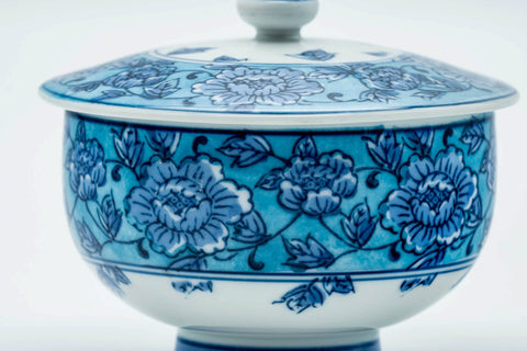 Close-up of the cup body detailing the blue floral pattern, lid on.