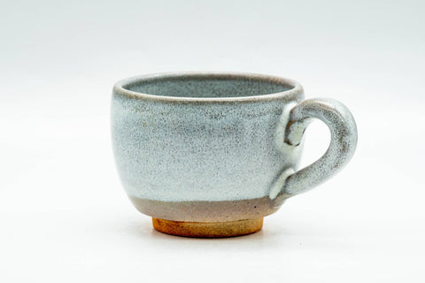 Side profile of the handled cup showing the milky-white glaze above the unglazed lower clay body.