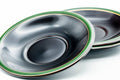 Two saucers in three-quarter view showing the concave black well bordered by a green rim.