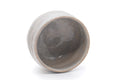 The chawan tilted to show its grey-glazed interior.