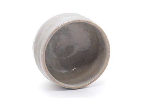 The chawan tilted to show its grey-glazed interior.