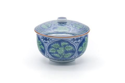 Front view of the lidded porcelain teacup showing the blue-green leaf motif.
