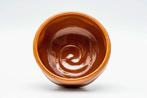 Overhead view looking into the glossy red interior of the chawan, showing a spiral