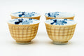 Pair of yellow ribbed yunomi teacups with blue floral-decorated interiors, viewed from the front
