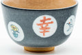 Front eye-level view of the grey celadon matcha bowl showing red kanji and floral roundels against the glaze.