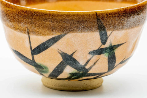 Close side view highlighting the green long-grass brushwork over the peach glaze.