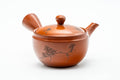 Three-quarter front view of a red shudei Tokoname-yaki kyusu engraved with kanji and leaf motifs, lid on, side handle right and spout left.