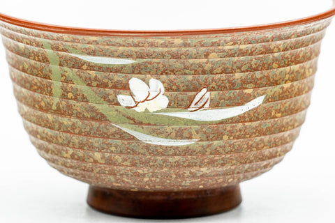 Close-up of the white floral decoration against the brown clay body