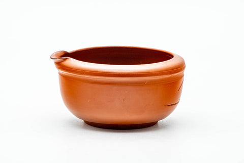 The katakuchi water cooler viewed from the side, highlighting its rounded reddish-brown clay body and pouring spout.
