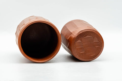 Japanese Teacups - Pair of Carved Red Shudei Tokoname-yaki Meoto Yunomi - one cup on its side beside an upright cup, showing the carved texture