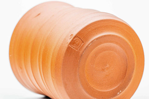 Teacup tilted to show the spiraling orange clay exterior and foot.