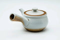 Side view of the white kyusu with the handle to the left, lid on.