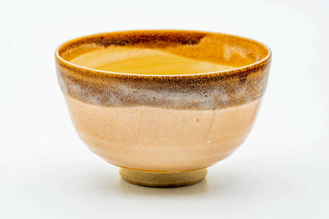 Front view of the Karatsu chawan showing the cream-peach glaze, green grass motif and a dark glazed rim.