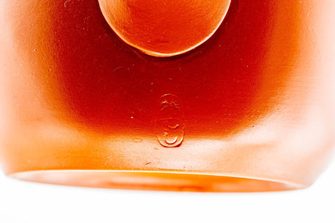Close-up of the lower body and base resting on a white surface, showing the smooth red shudei clay.