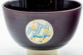 Wide front view showing a gold-and-blue geometric medallion on the purple body.