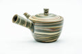 Side profile of the marbled teapot, spout to the left and hollow side handle facing the viewer.