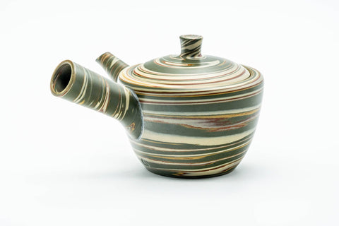 Side profile of the marbled teapot, spout to the left and hollow side handle facing the viewer.