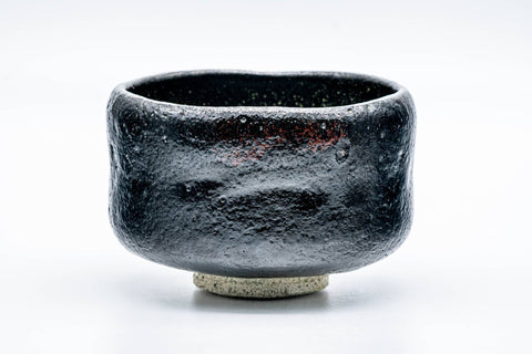 Three-quarter front view of the matte black raku bowl with its rough textured glaze