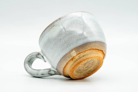 Cup tilted to show the handle and the transition from white glaze to raw clay near the base.